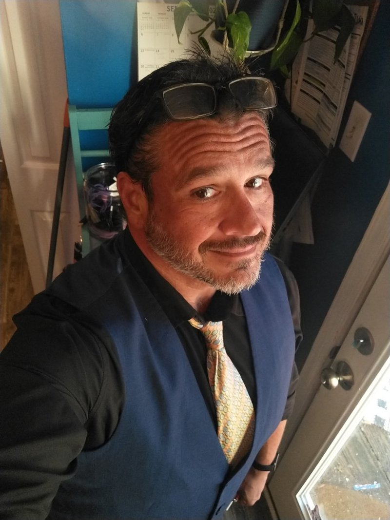 Jason Presson — dark vest and patterned tie, sunglasses pushed up, smiling at the camera
