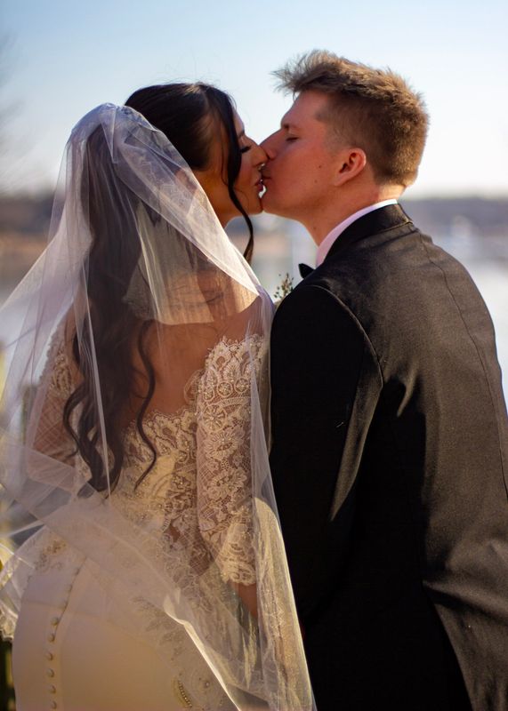 The Riemer wedding — the kiss, backlit by the veil